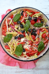 Greek salad in retro bowl. With tomatos, peppers, black olives, red onion, basil and feta cheese. Top view.