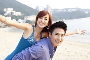 Sweet young couple playing piggyback on the beach of Repulse Bay, Hong Kong