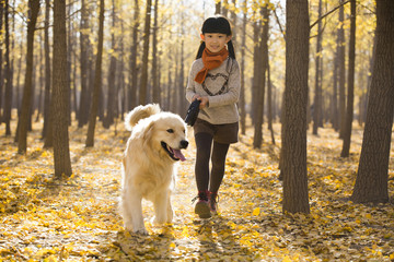 Little girl walking with dog in autumn woods