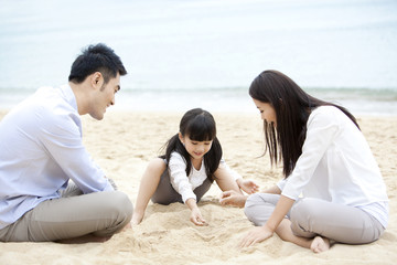 Cheerful young family playing with sand on the beach of Repulse Bay, Hong Kong