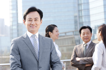 Confident businessman with partners in background