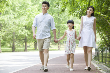 Naklejka premium Happy young family walking together in park