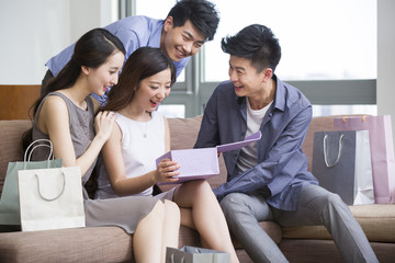 Happy young woman receiving gift from friends