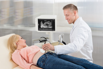 Doctor Moving Ultrasound Transducer On Pregnant Woman's Belly