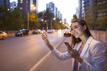 Young woman waiting for taxi with smart phone