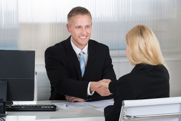 Businessman Shaking Hands With Female Candidate At Desk