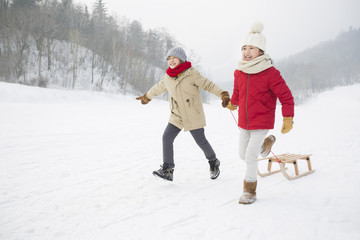 Fototapeta na wymiar Happy children running with sled on the snow