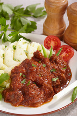 Goulash with mashed potatoes and tomato