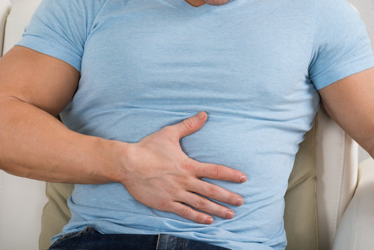 Man With Stomach Ache Sitting On Couch
