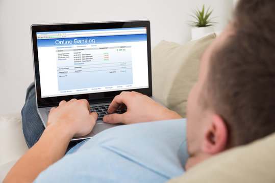 Man Using Online Banking On Laptop At Home