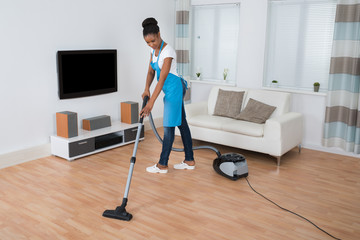 Woman Cleaning Floor With Vacuum Cleaner