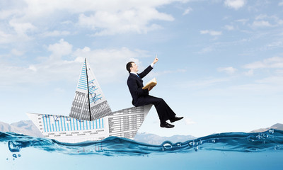 Businessman in boat made of paper