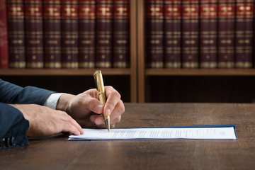 Lawyer Writing On Legal Documents At Desk - obrazy, fototapety, plakaty