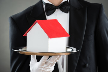Midsection Of Waiter Holding House Model In Tray