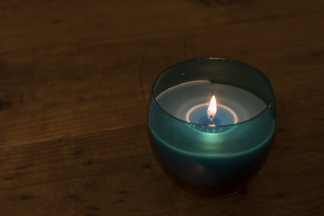 Obraz na płótnie Canvas Blue Glass Candle on a Wooden Table