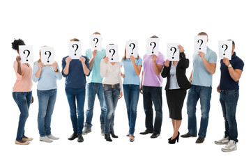 Obraz premium Creative Business Team Hiding Faces With Question Mark Signs