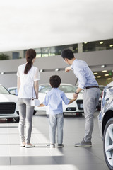 Young family looking at new car in showroom