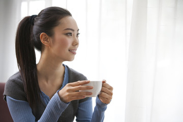 A young woman looking away while enjoying a cup of coffee