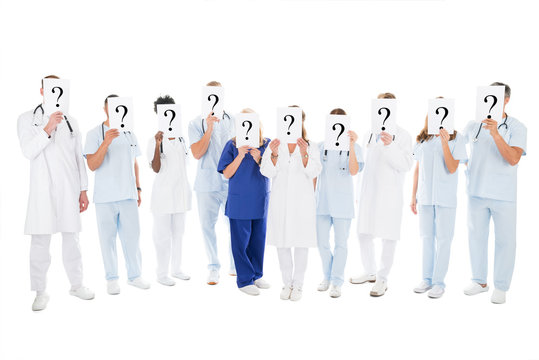 Medical Team Covering Faces With Question Mark Signs