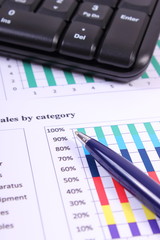 Pen and computer keyboard on financial graph, business concept