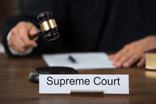 Supreme Court Nameplate With Judge Writing On Paper