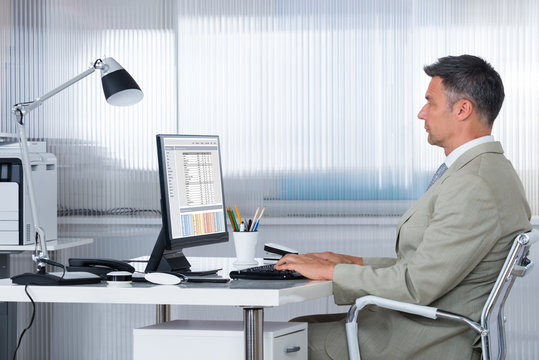 Male Accountant Using Computer At Desk