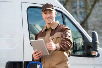 Smiling Delivery Man Holding Digital Tablet Against Truck