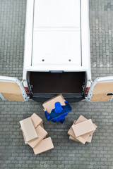 Delivery Man Unloading Cardboard Boxes From Van On Street