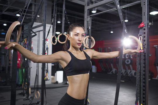 Young woman exercising with gymnastic rings at gym