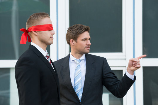 Businessman Assisting Blindfolded Partner