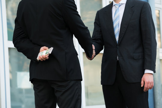 Businessman Holding Dollars While Shaking Hands With Partner