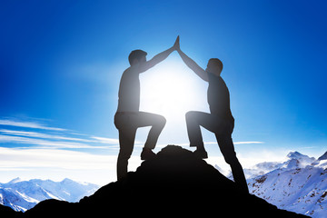 Male Friends Giving High Five On Mountain Peak