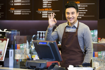 Male coffee store clerk doing OK sign