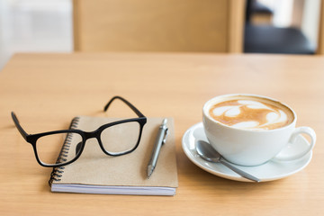 Coffee cup and notebook on grunge wooden background