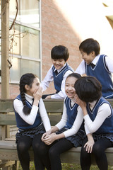 Five classmates talking on a school bench