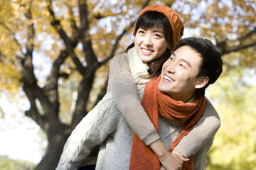 Young Couple Playing in a Park in Autumn