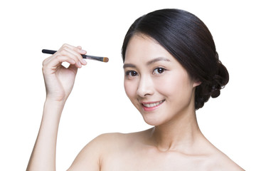 Fototapeta premium Beautiful young woman putting on make-up