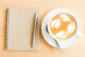 Coffee cup and notebook on grunge wooden background