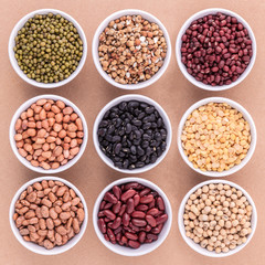 Mixed beans and lentils in the white bowl  on brown background.