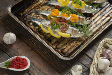Cooking fresh herring fish with garlic lemon dill cherry tomatoes