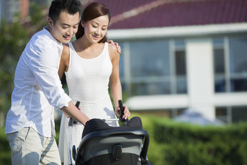 Young couple taking a walk with their baby in pram