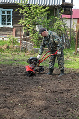 Obraz premium Man working in the garden preparing ground cultivator