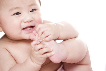 Cheerful baby girl holding her foot