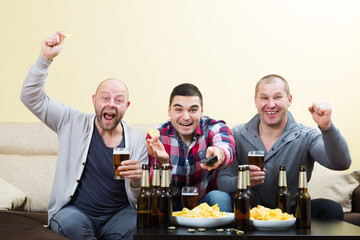 Three male friends sitting at table with beer