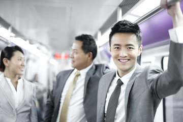 Cheerful businessman with partners in subway train