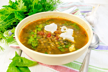 Soup lentil with spinach and feta in yellow bowl on board