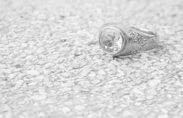 Closeup old diamond ring on blurred stone floor background in black and white tone