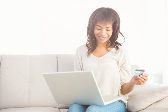 Smiling casual woman buying things with her laptop