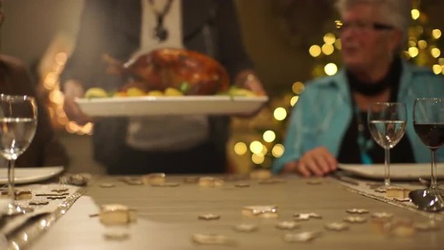 4k footage, dolly move closeup focus on roasted christmas turkey on dining table with seniors enjoying xmas eve, captured with atomos shogun

