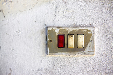 Old metal switch against a white plaster wall